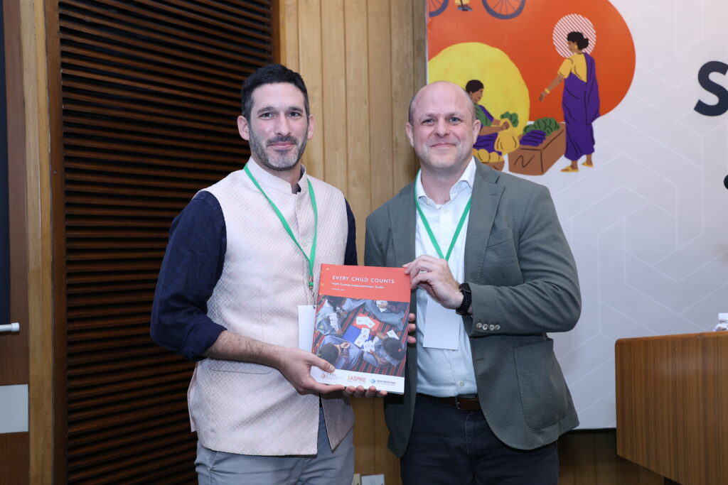 Noam Angrist, Academic Director of the What Works Hub for Global Education, and John Floretta, Global Deputy Executive Director of J-PAL, pose with the Every Child Counts Toolkit in Delhi, India in September 2025.